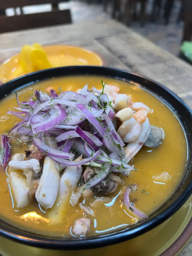 Encebollado mixto de mariscos seafood soup with red onions at a restaurant in Olon Ecuador.